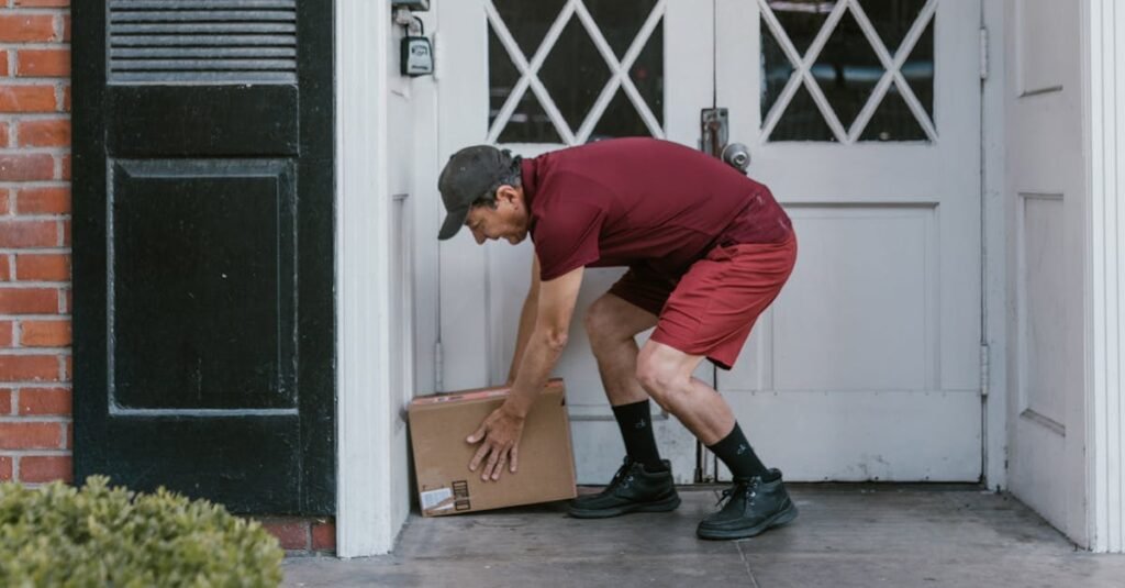 Delivery person in red uniform leaving a package at a home's front door.